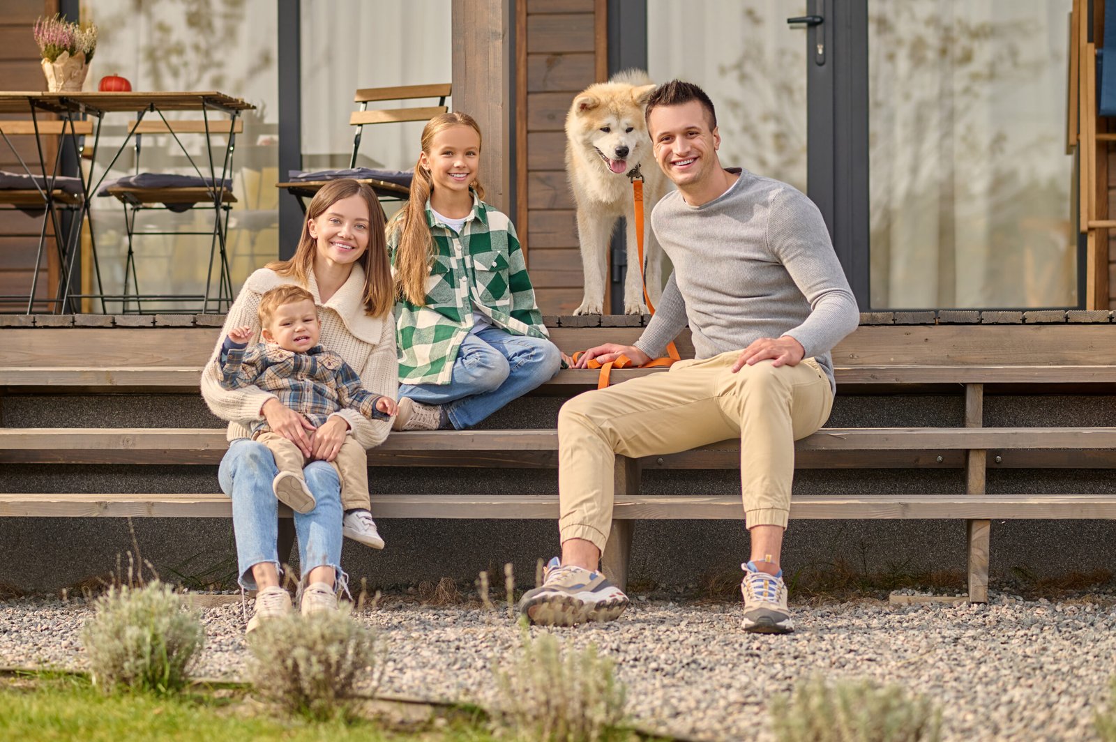 family sitting on steps looking at camera and dog
