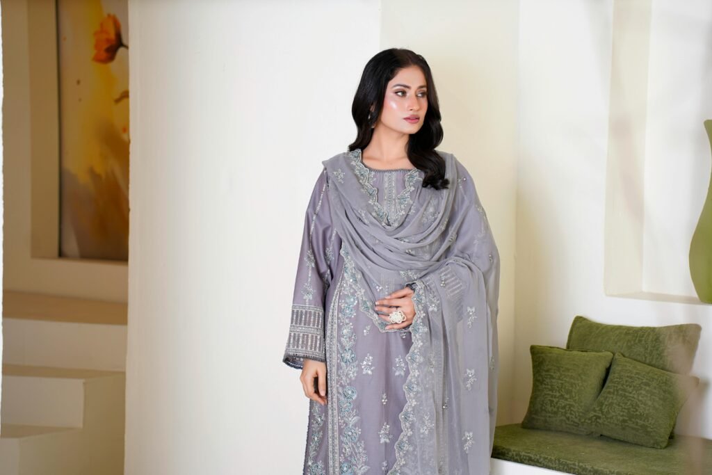 Model poses in a beautifully embroidered gray eastern dress indoors.